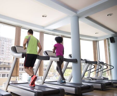 young people exercisinng a cardio on treadmill running chine in modern gymの写真素材