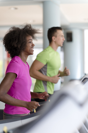 young people exercisinng a cardio on treadmill running machine in modern gymの写真素材