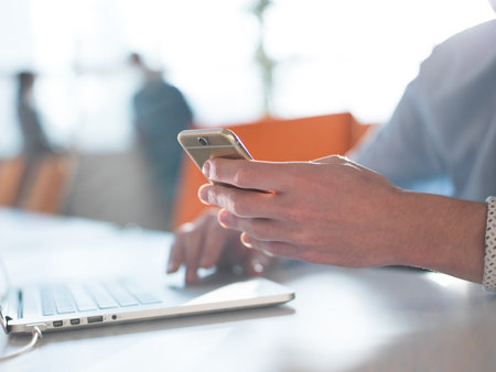 Young man holding on his smartphone in the office close up