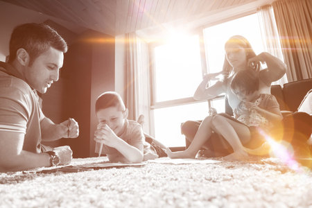 Happy Young Family Playing Together at home on the floor using a tablet and a children's drawing setの写真素材