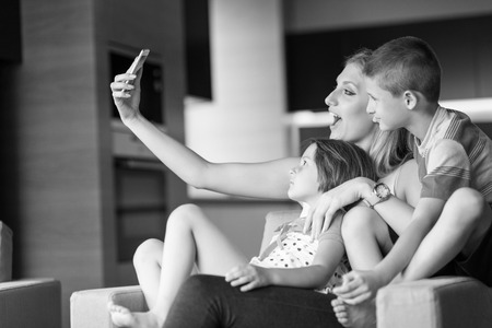 Happy family siting on sofa and using cell phone for video call  at homeの写真素材