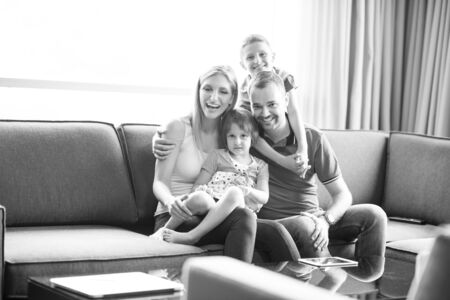 Happy Young Family Playing Together with tablet at home sitting on the sofaの写真素材