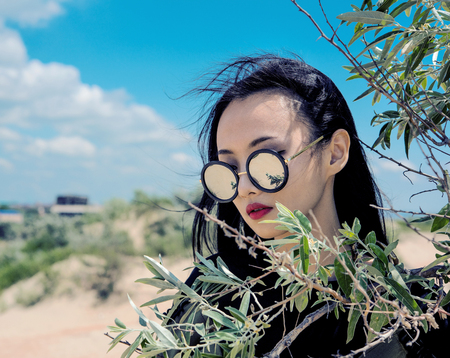 Oriental model on a sandy beach among the branches of the shrubの写真素材