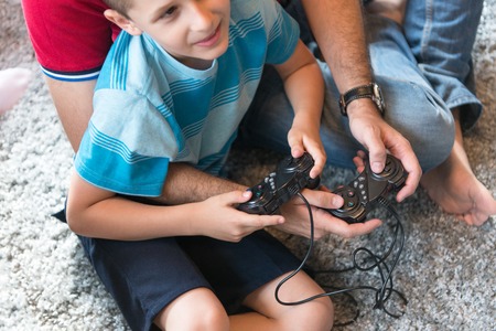 Happy family. Father, mother and children playing a video game Father and son playing video games together on the floorの写真素材