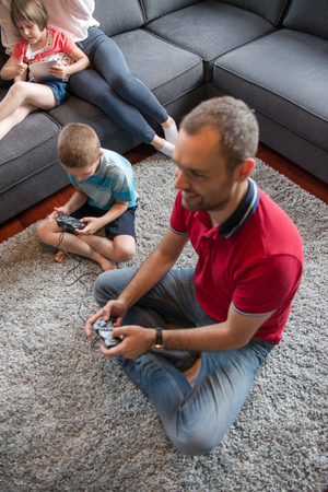 Happy family. Father, mother and children playing a video game Father and son playing video games together on the floorの写真素材