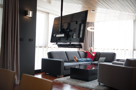 young handsome man enjoying free time watching television in his luxury home villa
