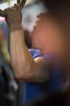 Fitness handsome man doing dipping exercise using rings in the gym