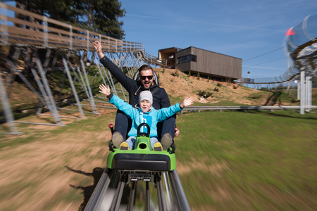 Excited father and son enjoys driving on alpine coasterの写真素材