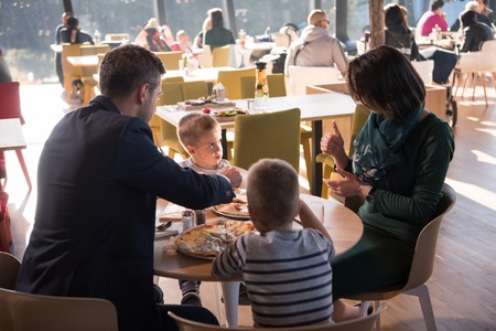 Young parents enjoying lunch time with their children at a luxury restaurantの写真素材