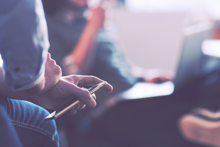 Young man holding on his smartphone in the office close upの写真素材