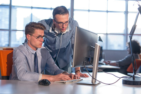 two business people using computer preparing for next meeting and discussing ideas with colleagues...