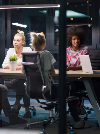 Multiethnic startup business team on meeting in modern night office interior brainstorming, working on laptopの写真素材