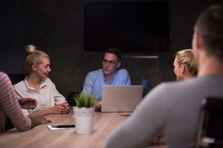 Multiethnic startup business team on meeting in modern night office interior brainstorming, working on laptopの写真素材