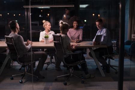Multiethnic startup business team on meeting in modern night office interior brainstorming, working on laptopの写真素材