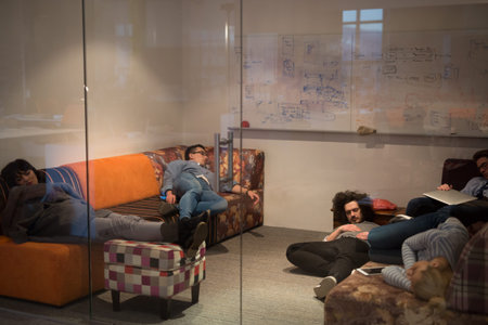 group of young casual software developer sleeping on  sofa during a work break in creative startup...
