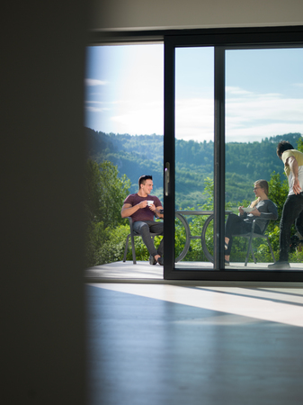 young beautiful handsome couple enjoying morning coffee and breakfast in front of their luxury home villaの写真素材