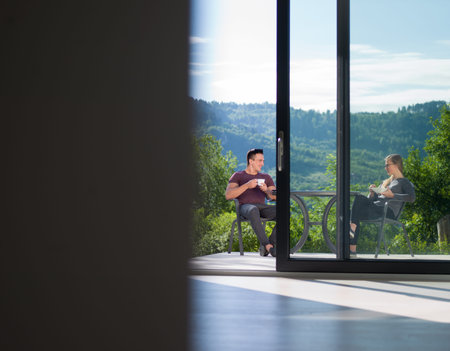 young beautiful handsome couple enjoying morning coffee and breakfast in front of their luxury home villaの写真素材