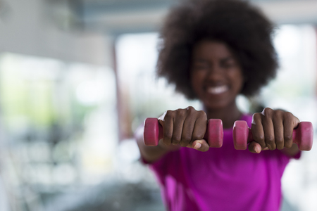 happy healthy african american woman working out in a crossfit gym on weight loss with dumbbellsの写真素材