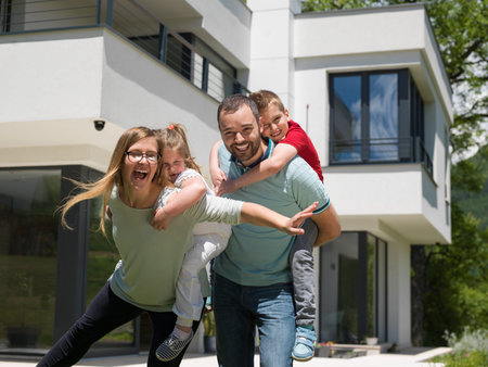 Portrait of young happy family with children in the yard in front of their luxury home of villaの写真素材