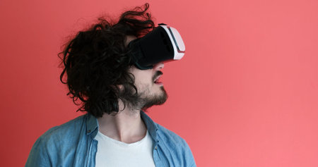 Happy man getting experience using VR headset glasses of virtual reality, isolated on red background
