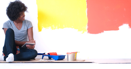 Portrait of a beautiful african american female painter sitting on floor near wall after painting.の写真素材
