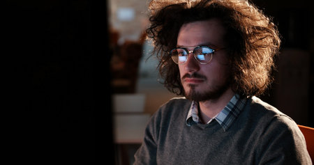 Young man working on computer at night in dark office. The designer works in the later time.