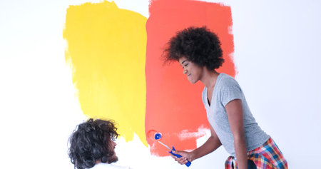 happy young multiethnic couple painting interior wall of new houseの写真素材