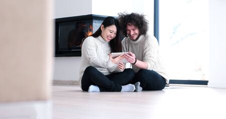 Young Couple sitting on the floor and using interent on digital tabletの写真素材