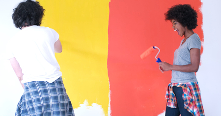 happy young multiethnic couple painting interior wall of new houseの写真素材