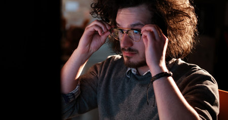 Young man working on computer at night in dark office. The designer works in the later time.
