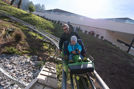 Excited father and son enjoys driving on alpine coasterの写真素材