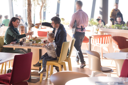 Young parents enjoying lunch time with their children at a luxury restaurantの写真素材