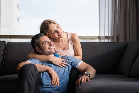 young handsome couple enjoys hugging on the sofa in their luxury home villaの写真素材