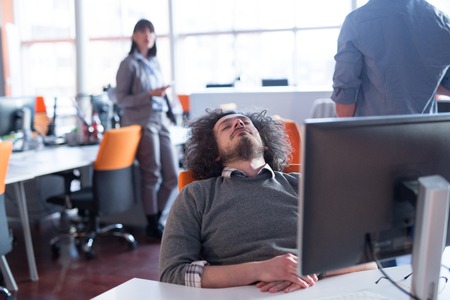 A time for relax. Young tired casual businessman relaxing at the desk in his officeの写真素材