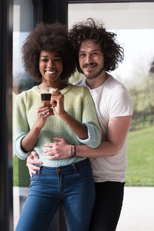 romantic happy young multiethnic couple enjoying morning coffee by the window in their luxury homeの写真素材