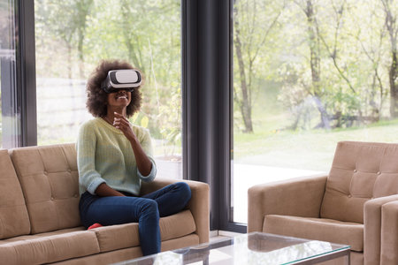 Happy african american girl getting experience using VR headset glasses of virtual reality at home