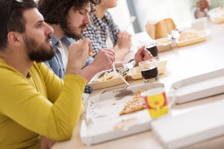 multiethnic group of happy friends spending time together with food and soda drinks, eating at home conceptの写真素材