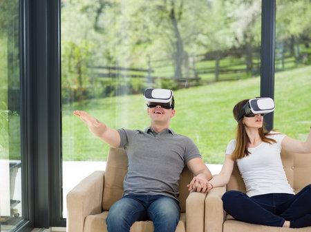 Couple using virtual reality headset in living room at home  people playing game with new trends...