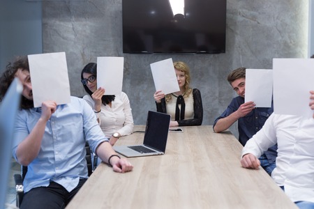 Portrait of a young business team holding a white paper over their face  in the startup officeの写真素材