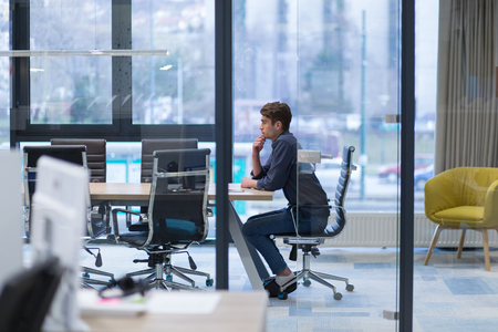 A time for relax. Young tired casual businessman relaxing at the desk in his officeの写真素材