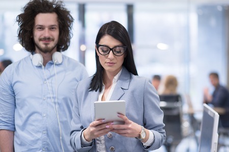 business people using tablet  computer while preparing for next meeting colleagues in the background discussing ideas  at startup officeの写真素材