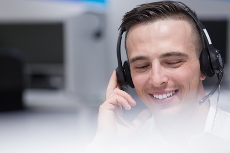young smiling male call centre operator doing his job with a headsetの写真素材