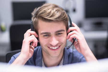 young smiling male call centre operator doing his job with a headsetの写真素材