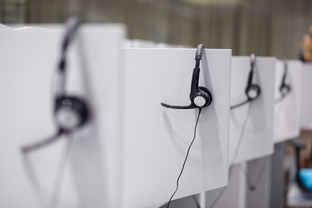 Headphones hanging on cubicle partition in empty call center officeの写真素材