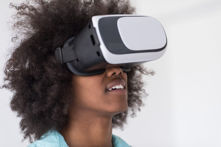 Happy african american girl getting experience using VR headset glasses of virtual reality, isolated on white backgroundの写真素材