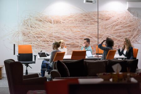 Group of a young business people discussing business plan at modern startup late night office buildingの写真素材