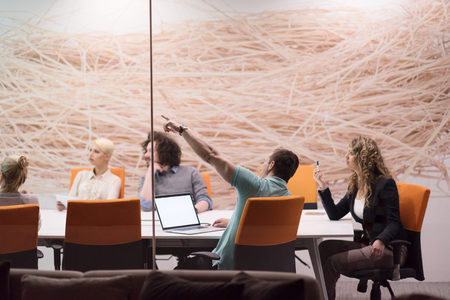 Group of a young business people discussing business plan at modern startup late night office buildingの写真素材