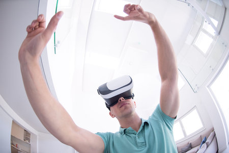 happy man getting experience using VR-headset glasses of virtual reality at home
