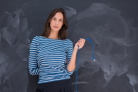 portrait of a young woman holding a internet cable in front of chalk drawing boardの写真素材