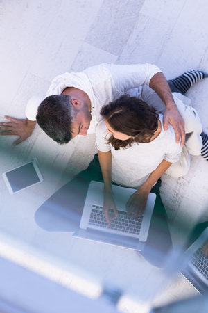 top view of a young couple relaxing at home with tablet and laptop computers reading on the floor